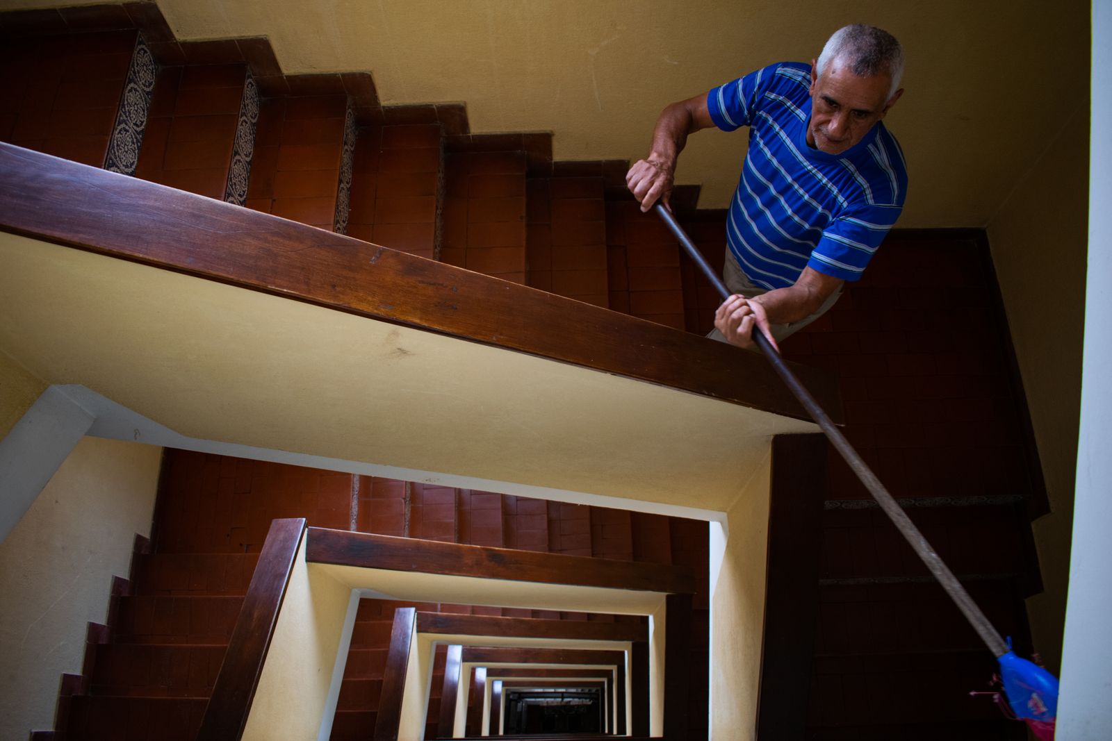 Agent d’entretien lavant les marches d’une cage d’escalier d’immeuble